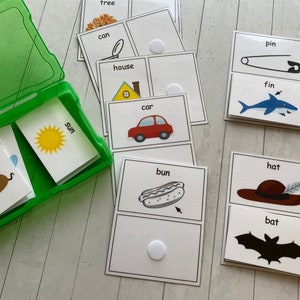 May include: A set of 10 flash cards with images and words for early learners. The cards feature a variety of objects, including a tree, can, house, car, sun, mouse, bun, hat, fin, and pin. The cards are designed to help children learn new words and concepts.