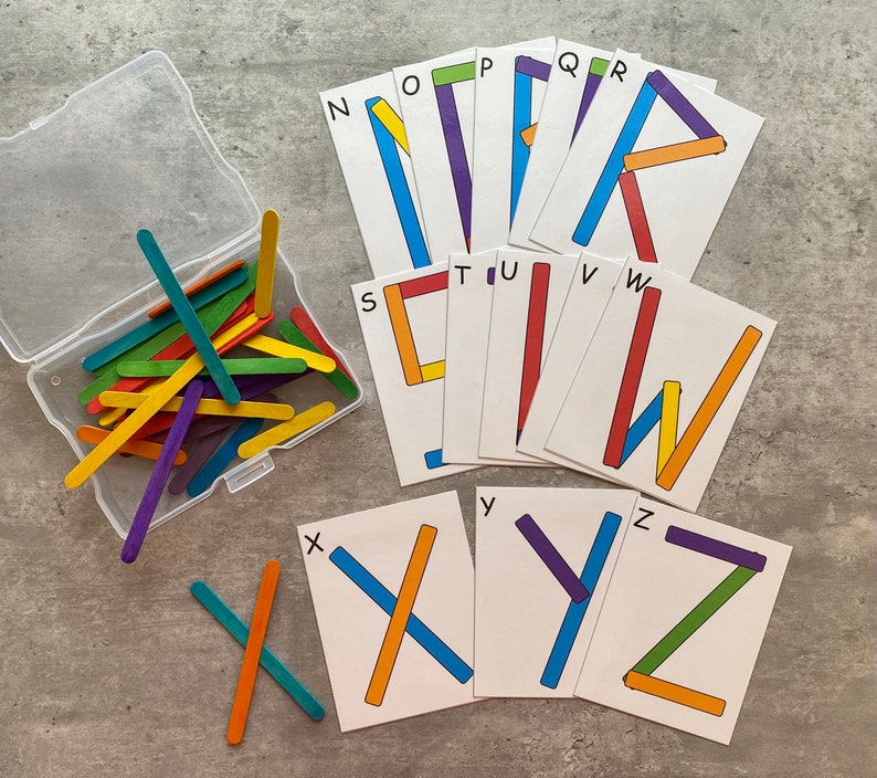 May include: A set of alphabet letter cards with colorful wooden sticks to create the letters. The letters are printed in black on white cards. The cards are arranged in alphabetical order from N to Z.