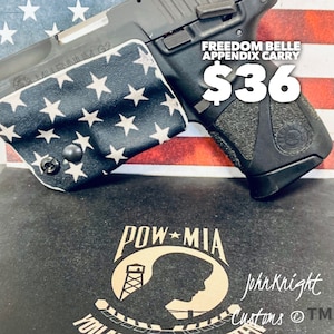May include: A black handgun with a white and blue American flag pattern on the holster. The text "FREEDOM BELLE APPENDIX CARRY" and "$36" are visible. The text "POW MIA" and "John Knight Customs TM" are also visible.