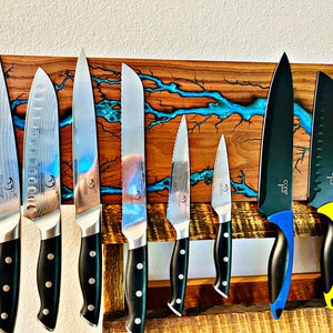 May include: A wooden magnetic knife holder with a blue epoxy resin inlay. The holder has eight knives, including a chef's knife, a paring knife, and a bread knife.
