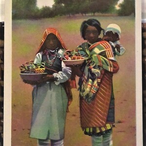 May include: Two women and a child are selling pottery at an outdoor market. The women are wearing traditional clothing and the child is wearing a white shirt and a white hat. The women are holding baskets of pottery and the child is holding a small doll. The sign reads "Pueblo Pottery Vendors, Albuquerque, New Mexico."