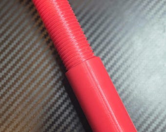 May include: A bright red plastic bolt and nut assembly. The bolt features a hexagonal head and a long threaded shaft, while the cylindrical nut is screwed onto the lower portion of the shaft. The object has a smooth, matte finish throughout.