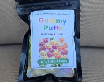 May include: A black resealable pouch containing freeze-dried candy. The label reads The Wayward Wildflower, Gummy Puffs, Freeze-Dried Candy, and Trial Size 4 Bears, featuring a colorful image of small bear-shaped candies.