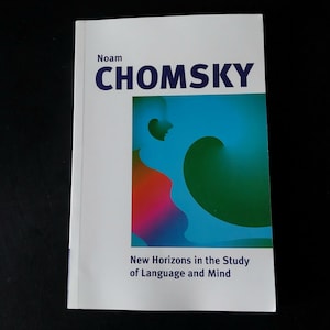Puede incluir: Un libro blanco titulado "CHOMSKY" de Noam, con un diseño abstracto colorido en azul, verde y rojo. El título del libro está en letras grandes y en negrita. El subtítulo dice "New Horizons in the Study of Language and Mind."