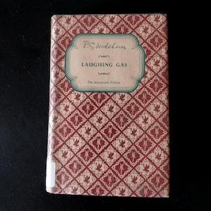 May include: A hardcover book titled Laughing Gas by P.G. Wodehouse, The Autograph Edition. The cover features a repeating dark red and cream geometric pattern with a central green-bordered label containing the title and author name in black text.