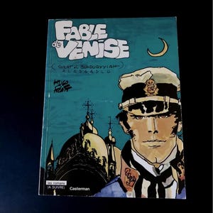 May include: A comic book titled "Fable de Venise" with a teal background and a drawing of a man in a naval uniform. The cover features the title in large white letters and the author's name.