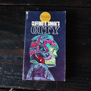 May include: A paperback book cover with a colorful illustration of a skull-like head with a house in the background. The book title is "Clifford D. Simak's City" and the cover also includes a gold sticker that says "Winner of the Hugo Award for Science Fiction".