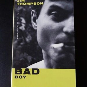May include: A book cover with a black and white photo of a man's face. The title of the book is "BAD BOY" in large, bold, black letters on a yellow background. The author's name, "JIM THOMPSON", is printed in black above the photo. The text "Read Jim Thompson and take a tour of hell." is printed in black at the bottom of the cover.