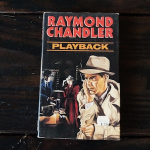 Può includere: Un libro tascabile vintage intitolato "Playback" di Raymond Chandler. La copertina presenta un uomo con impermeabile e fedora, con un'illustrazione in stile noir di altre figure sullo sfondo. Il libro ha un'etichetta con il prezzo.