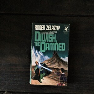 May include: A paperback book cover with a green and white design. The title is "Dilvish, The Damned" by Roger Zelazny. The cover features a man in green armor holding a sword and a man in black armor holding a sword. The background is a snowy mountain range.