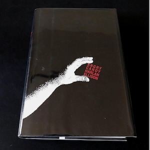 May include: A black hardcover book with a white, stylized hand design. The title "Angry Candy" and author "Harlan Ellison" are printed in red. The book is displayed against a black backdrop.