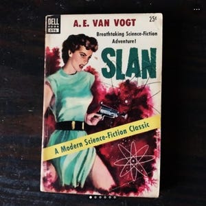 Könnte beinhalten: Ein Vintage-Paperback-Buchcover mit einer Frau, die eine futuristische Waffe hält. Das Cover ist rot, weiß und grün mit einer Schwarzweißillustration einer Galaxie. Der Titel des Buches lautet "SLAN" und der Autor ist A.E. Van Vogt. Das Buch ist ein Science-Fiction-Klassiker.