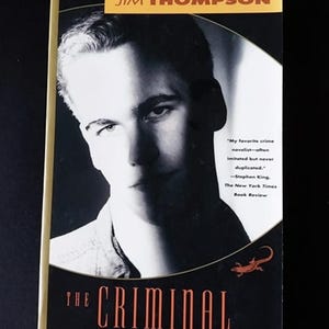 May include: A black and white photo of a man on the cover of a paperback book titled "The Criminal" by Jim Thompson. The book cover features a quote from Stephen King about the author.