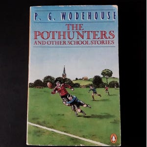 May include: A paperback book titled The Pothunters and Other School Stories by P. G. Wodehouse. The cover features a light blue sky above a green field where figures in red and blue jerseys play rugby. A small orange penguin logo is at the bottom.