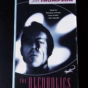 May include: A book cover with a black and white photo of a man with a serious expression. The title of the book is "THE ALCOHOLICS" in pink letters. The author's name, "JIM THOMPSON", is printed in white letters at the top of the cover.