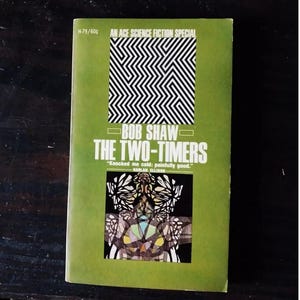 May include: A green paperback book cover with a black and white geometric design, the title "THE TWO-TIMERS" by Bob Shaw, and a quote by Harlan Ellison.