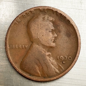 May include: A copper 1930-D Lincoln penny with the words "IN GOD WE TRUST" and "LIBERTY" visible on the coin.