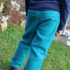 May include: A pair of teal blue fleece sweatpants with a dark blue waistband.