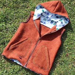 May include: A brown hooded vest with a zipper closure and two pockets. The vest is lined with a blue and green patterned fabric.