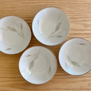 May include: Four white ceramic bowls with a wheat design. The bowls are all the same size and shape, and they have a simple, elegant design.