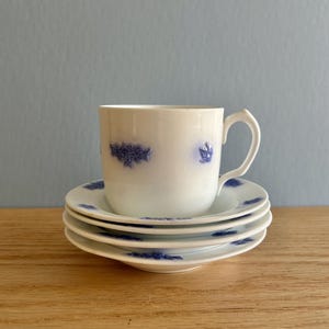 May include: A white porcelain teacup and saucer set with a blue floral pattern. The cup has a handle and the saucer is decorated with a delicate floral design.