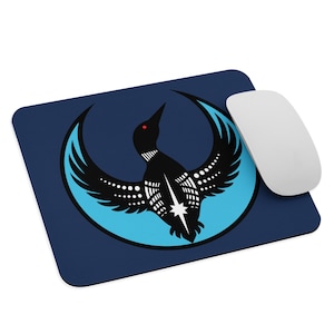 May include: A navy blue mousepad featuring a stylized black bird design with a light blue crescent and a white star. The bird has red eyes and white dot and line details. A white computer mouse is next to the mousepad.