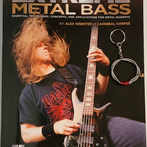 May include: A book titled "Extreme Metal Bass" by Alex Webster of Cannibal Corpse. The cover features a black and white photo of a man playing a black and white bass guitar. The book is for metal bassists and includes essential techniques, concepts, and applications.