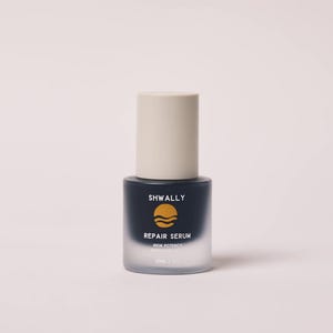 May include: A skincare serum bottle with a beige cylindrical cap and a dark blue base. The bottle is labelled "SHWALLY" and "REPAIR SERUM" with a graphic of three horizontal lines. The bottle contains 30ml / 1.0 fl oz.