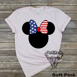 May include: A soft pink t-shirt featuring a black Mickey Mouse head design. The bow on Mickey's head is red, white and blue with a pattern of stars and stripes, resembling the Union Jack.