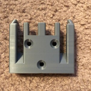 May include: A gray plastic wall mount with four slots and three holes for mounting screws.