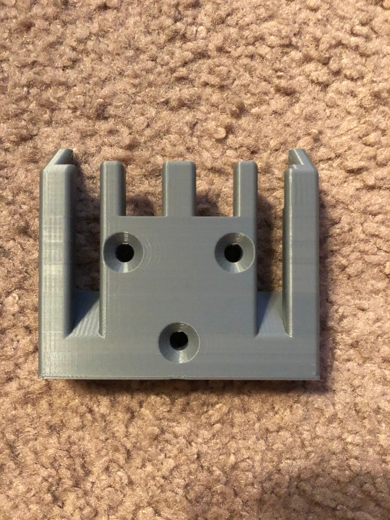 May include: A gray plastic wall mount with four slots and three holes for mounting screws.