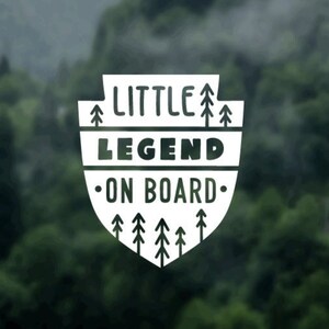 May include: White sticker with a shield shape and the text "LITTLE LEGEND ON BOARD" with stylized trees around the text.