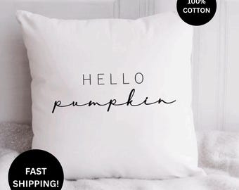 May include: A square white throw pillow featuring the black text HELLO pumpkin centered on the front. The pillow is made of 100% cotton fabric and has a smooth, clean appearance with a minimalist design that highlights the bold black lettering.