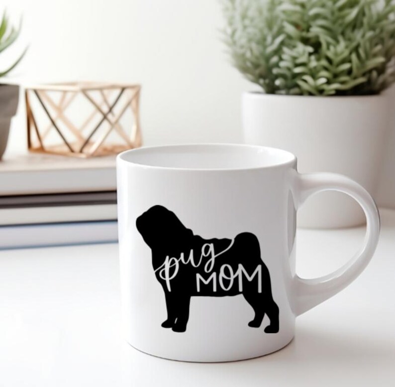May include: White ceramic mug with a black silhouette of a pug and the text "pug mom" in white.