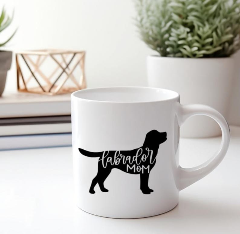 Pu&ograve; includere: Tazza in ceramica bianca con una silhouette nera di un labrador retriever e il testo "labrador mom" in scrittura nera.