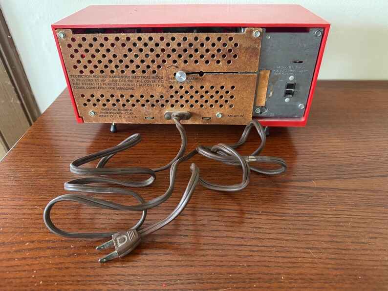 Puede incluir: Radio vintage rojo AM/FM con un cable marr&oacute;n y un cable de alimentaci&oacute;n negro. La parte posterior de la radio tiene una etiqueta que dice "ADVERTENCIA: PELIGRO DE DESCARGA EL&Eacute;CTRICA DE ALTA TENSI&Oacute;N. EN CASO DE DUDA, CONSULTE LAS INSTRUCCIONES CORRECTAS. NO ABRIR. SI EL CABLE DE ALIMENTACI&Oacute;N EST&Aacute; DA&Ntilde;ADO, RETIRE ESTE CABLE COMPLETAMENTE PARA LAS REPARACIONES."
