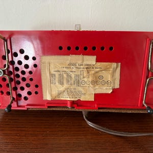 Puede incluir: Radio vintage roja con una etiqueta en blanco y negro que dice "Modelo 824 Serie II 115 Voltios 60 Ciclos AC Solo 32 Vatios".