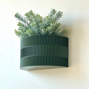 a green planter hanging from a wall