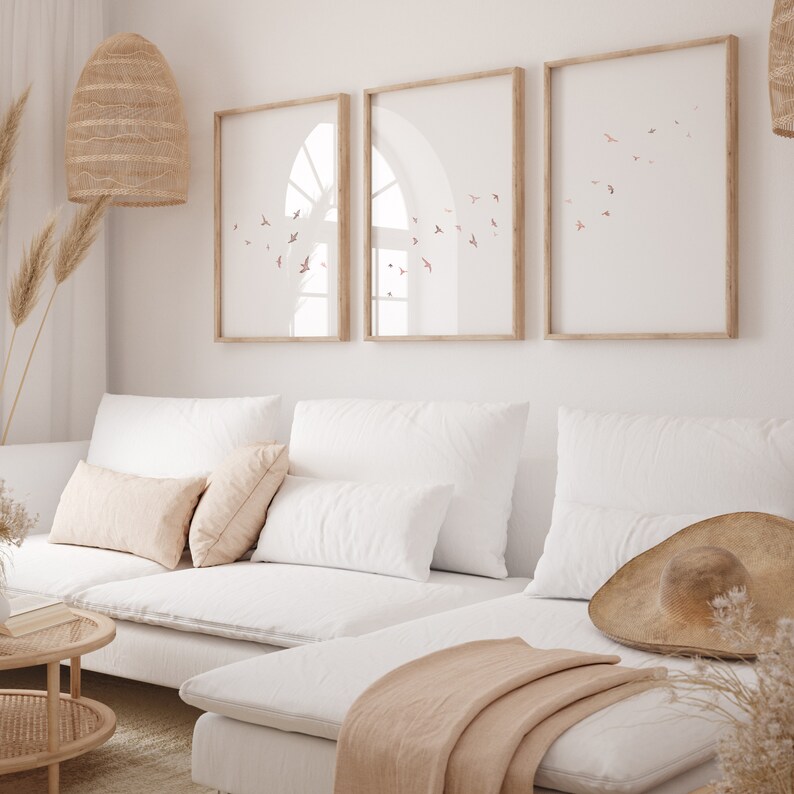 Puede incluir: Un sof&aacute; seccional blanco con una manta de color beige claro y un sombrero de paja en el asiento. El sof&aacute; est&aacute; frente a una pared blanca con tres impresiones enmarcadas de p&aacute;jaros volando.