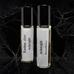 Puede incluir: Dos pequeños frascos de vidrio con tapas negras y etiquetas blancas. Las etiquetas tienen texto negro que dice "London after midnight" y "midnight" con las palabras "Victorian Oddities" debajo.