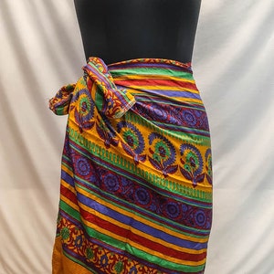 May include: A colorful wrap skirt with a yellow background, green, red, and purple stripes, and a floral pattern.