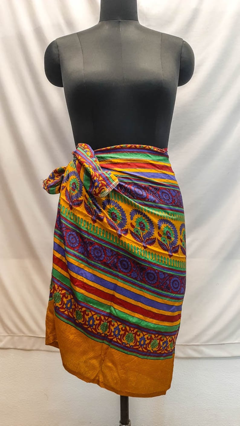 May include: A colorful wrap skirt with a yellow background, green, red, and purple stripes, and a floral pattern.