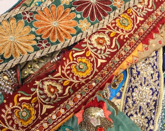 May include: Close-up of colorful fabric scraps with intricate embroidery and embellishments. The fabric is a mix of red, green, gold, and blue, with sequins and beads sewn into the designs.