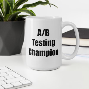 May include: White ceramic mug with black text that reads "A/B Testing Champion".