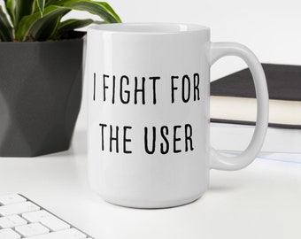 May include: White ceramic coffee mug with black text that reads "I fight for the user".