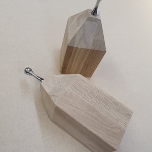 May include: Two wooden house-shaped bottle stoppers with silver metal tops.