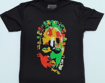 May include: Black t-shirt featuring a colourful graphic print of a person's face. The face is made up of red, yellow, green, and white squares. The shirt has a tag that says "MAROON CULTURE APPAREL".