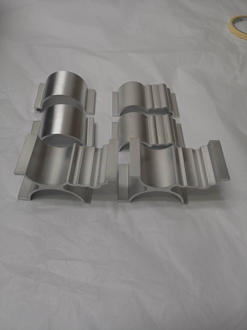 May include: Set of six silver metal brackets with a decorative design. The brackets are made of aluminium and have a smooth, polished finish.