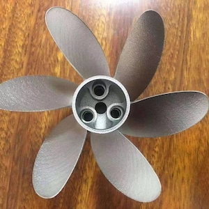 Puede incluir: Una h&eacute;lice de seis palas de color plateado con un cubo central. La h&eacute;lice tiene un acabado liso y met&aacute;lico.