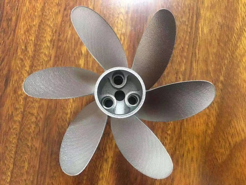 Puede incluir: Una h&eacute;lice de seis palas de color plateado con un cubo central. La h&eacute;lice tiene un acabado liso y met&aacute;lico.